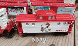 Un ensemble de train de Noël Charlie Brown en O gauge avec des wagons Lionel, une locomotive Snoopy et un fourgon de queue.