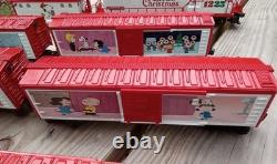 Un ensemble de train de Noël Charlie Brown en O gauge avec des wagons Lionel, une locomotive Snoopy et un fourgon de queue.