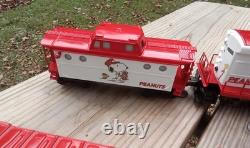 Un ensemble de train de Noël Charlie Brown en O gauge avec des wagons Lionel, une locomotive Snoopy et un fourgon de queue.